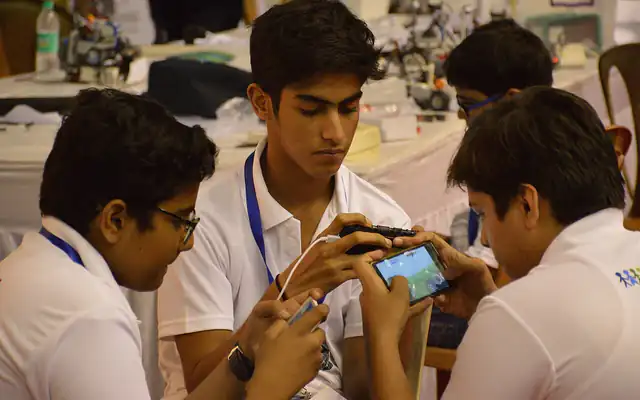 Group of young friends playing a mobile game together on their phones